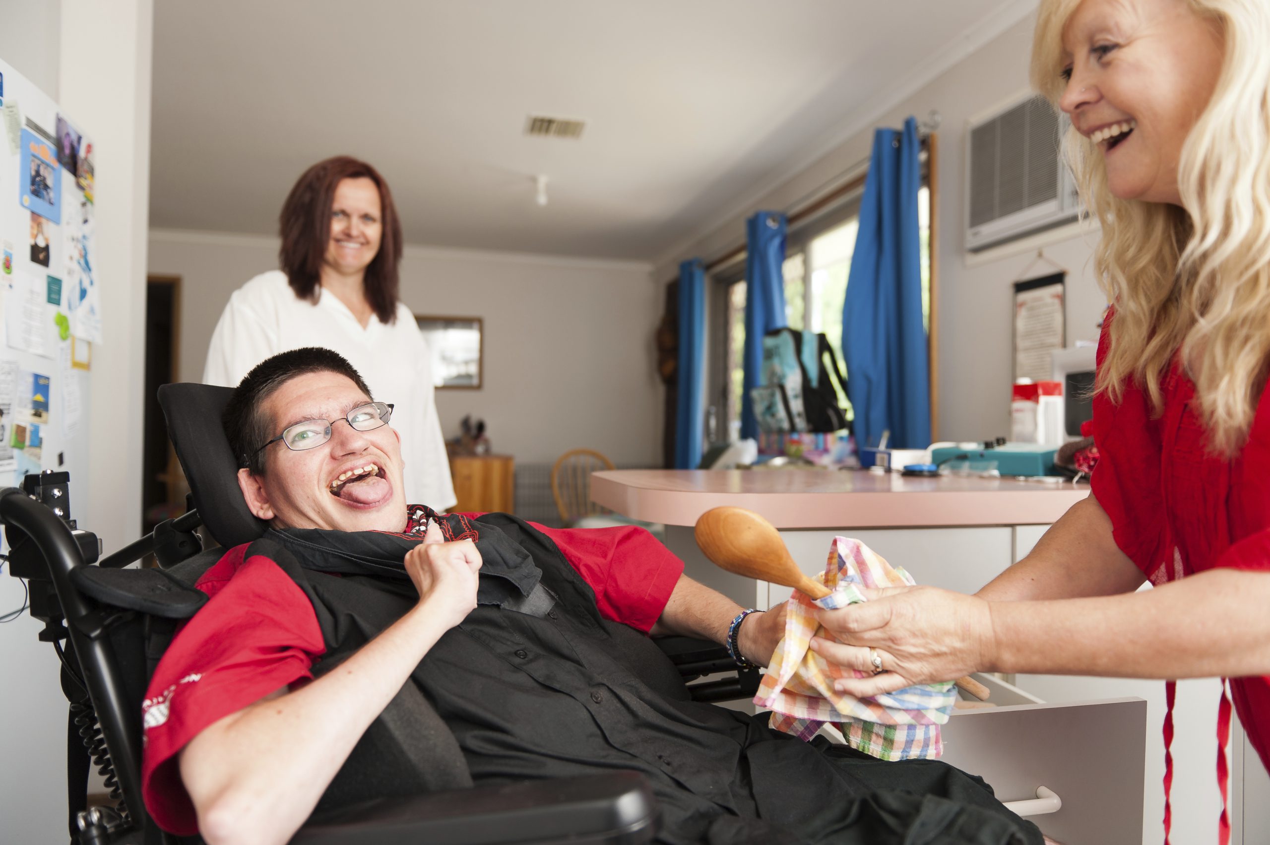 Man in wheelchair being assisted to wipe dry a spoon